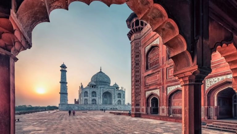 The Taj Mahal at dawn framed by an arch of the mosque in the Agra complex